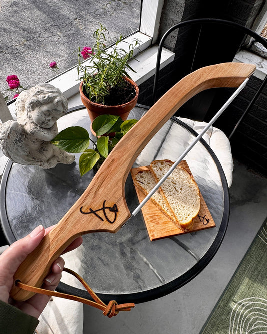 Wooden bow held by a person with a small table and plants in the background