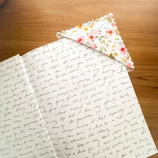 Floral fabric corner bookmark tucked over the page of an open book