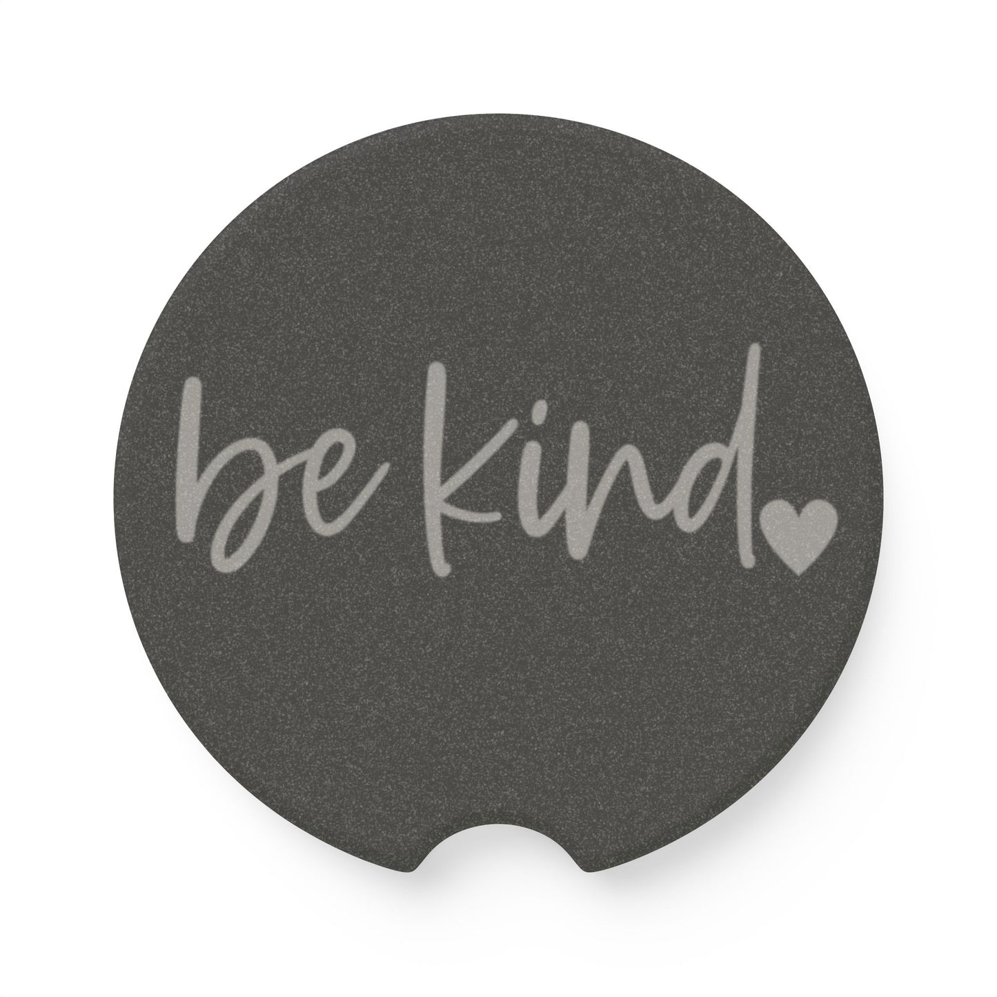 Round dark gray coaster with 'be kind' text and heart symbol on a white background