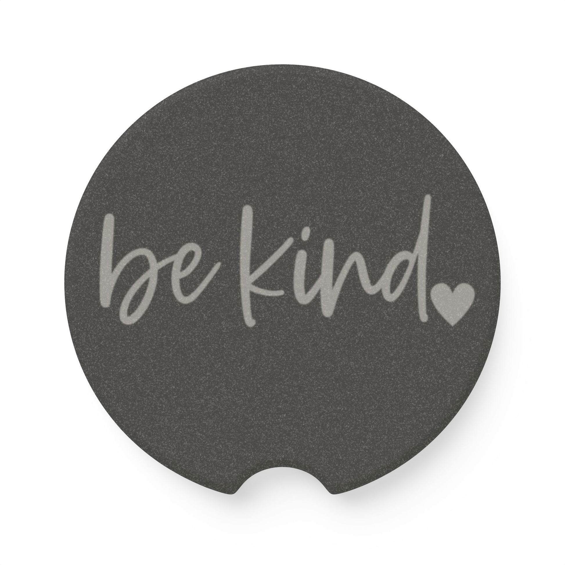 Round dark gray coaster with 'be kind' text and heart symbol on a white background