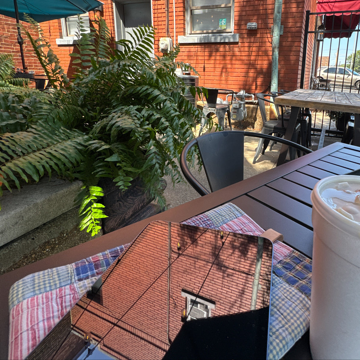 Rescued vintage quilt book and iPad sleeve in use on an outdoor coffee shop table beside an iPad and iced drink.