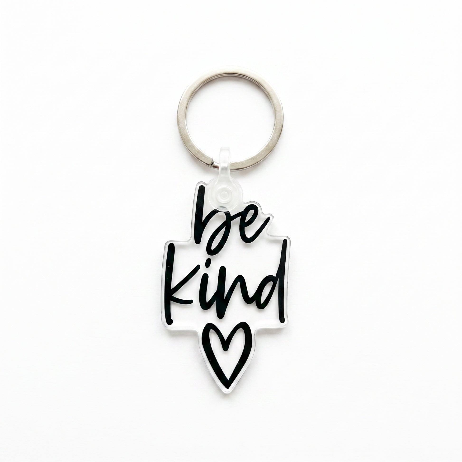 Clear acrylic Be Kind keychain with black script lettering and heart detail on white background