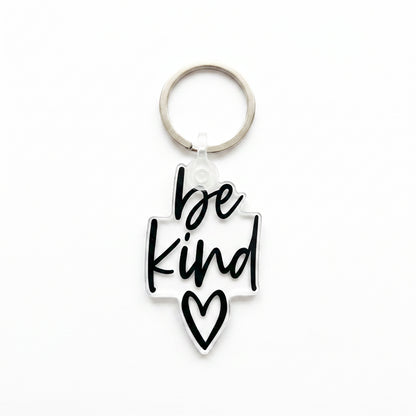 Clear acrylic Be Kind keychain with black script lettering and heart detail on white background