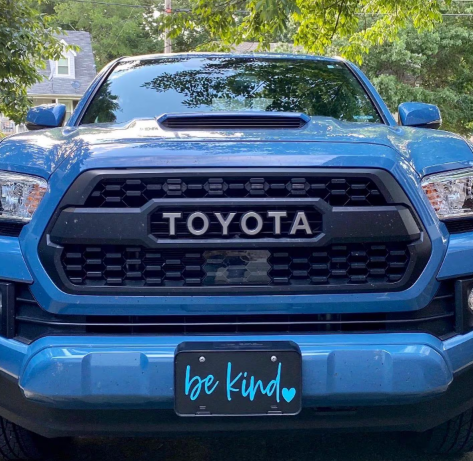 Black Be Kind decorative front plate installed on blue Toyota truck