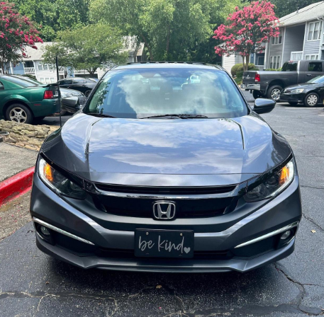 Black Be Kind plastic license plate installed on black Honda sedan
