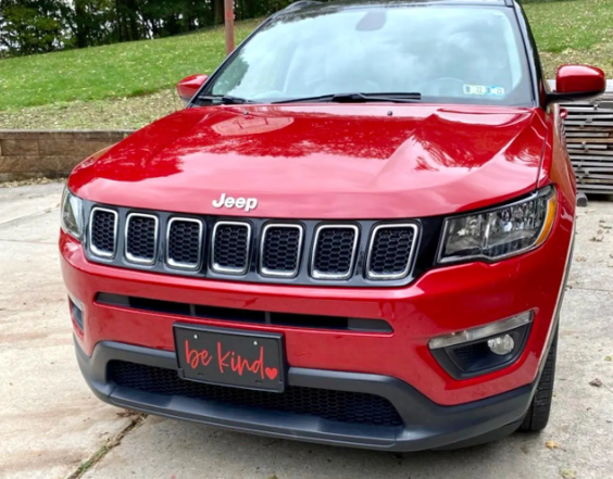 Be Kind decorative front license plate mounted on red Jeep SUV