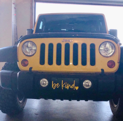 Black Be Kind front license plate mounted on yellow Jeep