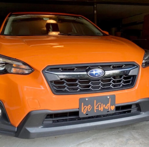 Be Kind front license plate mounted on orange Suburu