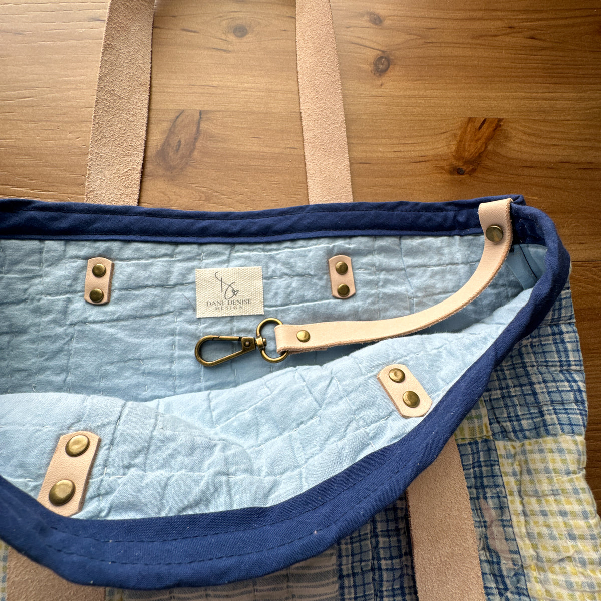 Interior of rescued vintage quilt market tote showing vegetable-tanned leather key keeper, leather handle attachments, and Dani Denise Design label.