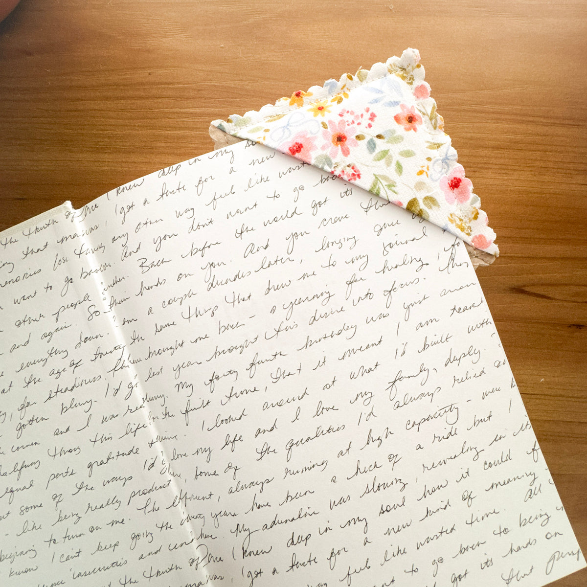 Floral fabric corner bookmark tucked over the page of an open book
