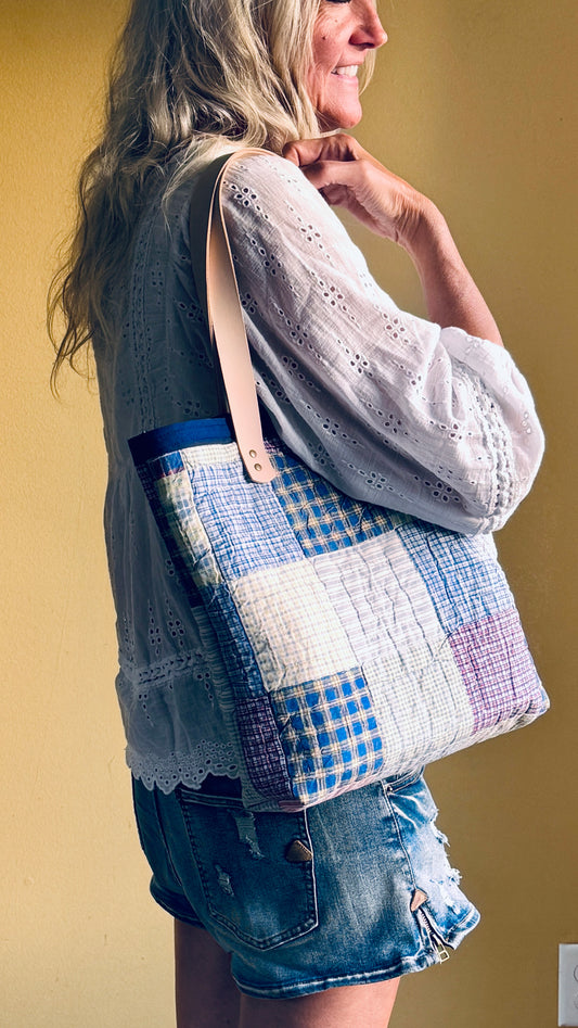 Woman carrying a one-of-a-kind rescued vintage quilt market tote with vegetable-tanned leather handles over her shoulder.