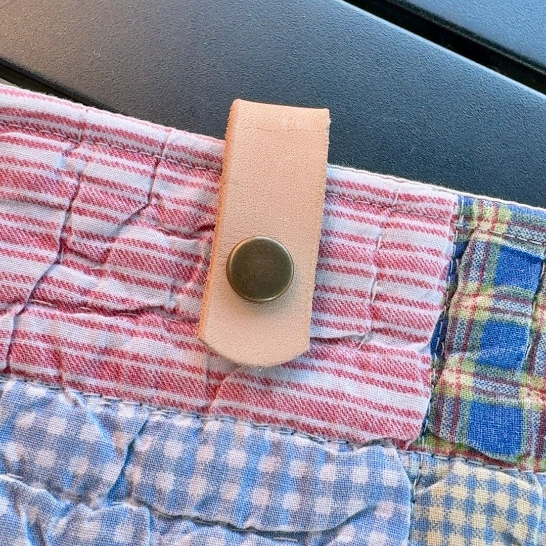 Close-up of vegetable-tanned leather snap closure on rescued vintage quilt book and iPad sleeve.