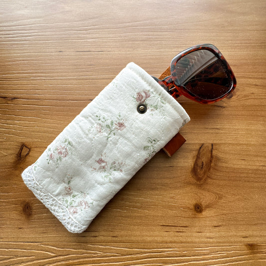Light floral rescued quilt glasses pouch shown holding sunglasses