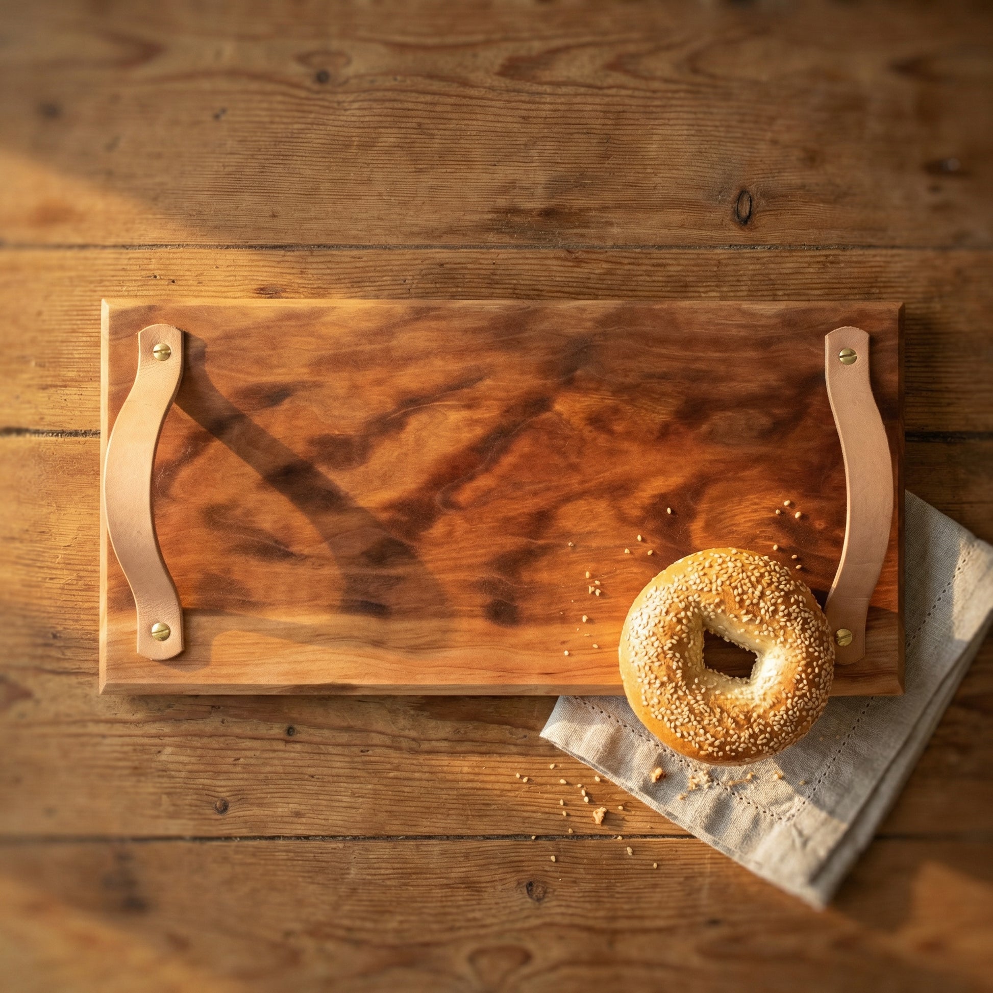 Handmade sycamore serving tray with leather handles styled with bagel on rustic wooden kitchen table