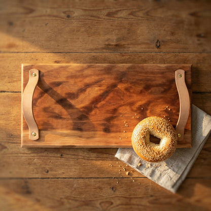 Handmade sycamore serving tray with leather handles styled with bagel on rustic wooden kitchen table