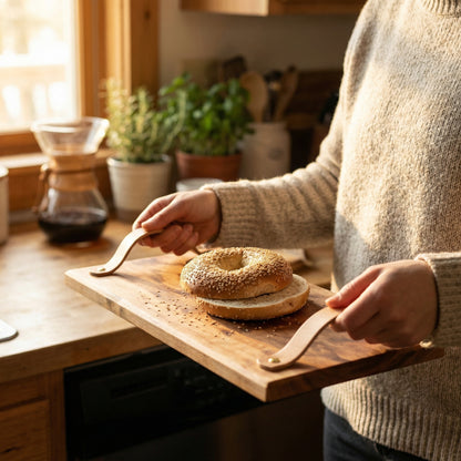 Woman carrying handmade sycamore serving tray with leather handles and sliced bagel