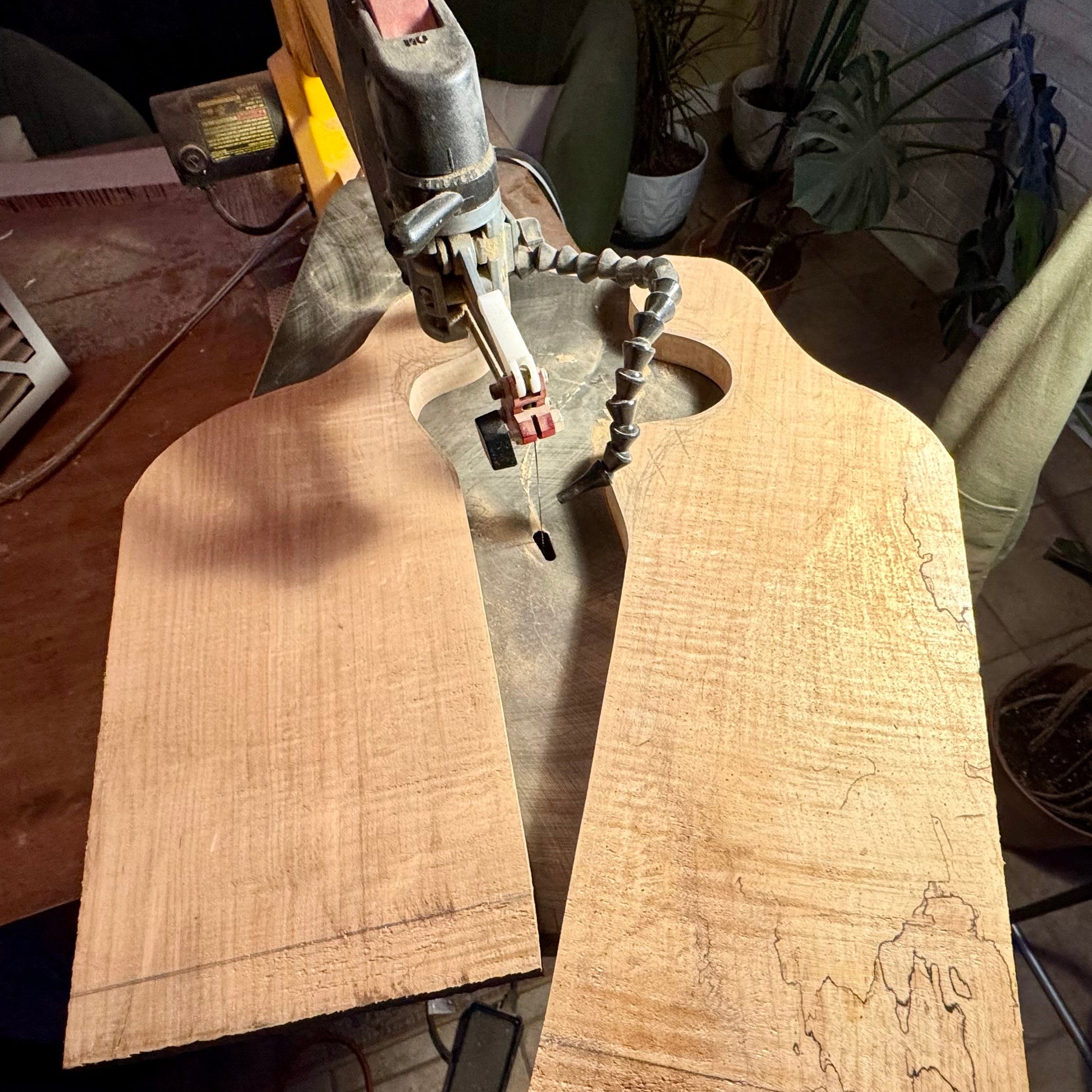 Cutting a handmade walnut charcuterie board on a scroll saw during the shaping process